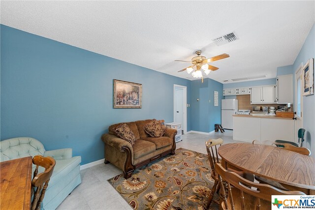 living room featuring ceiling fan and a textured ceiling