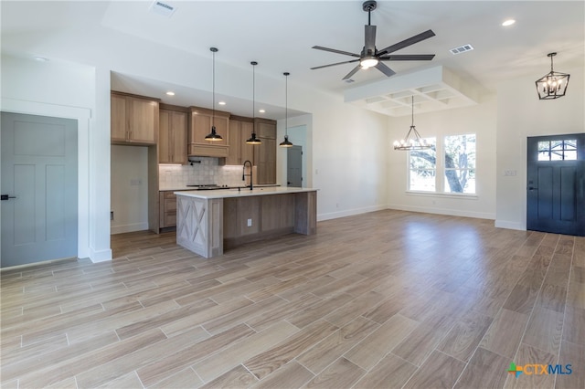 kitchen featuring hanging light fixtures, a large island, ceiling fan with notable chandelier, and light hardwood / wood-style flooring