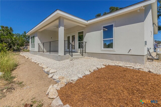 back of property featuring ceiling fan and a patio