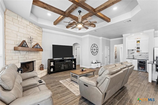 living area featuring a dry bar, beverage cooler, visible vents, a stone fireplace, and wood finish floors