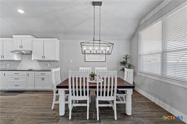 dining area featuring baseboards, lofted ceiling, and wood tiled floor