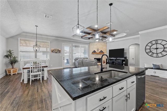 kitchen with open floor plan, a kitchen island with sink, a sink, white cabinetry, and dark stone counters