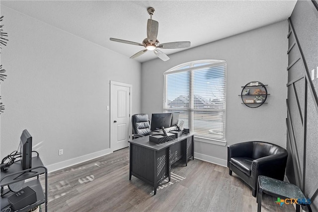 home office with ceiling fan, a textured ceiling, baseboards, and wood finished floors