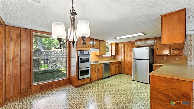 162 Lone Oak St, Seguin, TX 78155 - kitchen featuring stainless steel appliances, brown cabinetry, light countertops, under cabinet range hood, and a textured ceiling