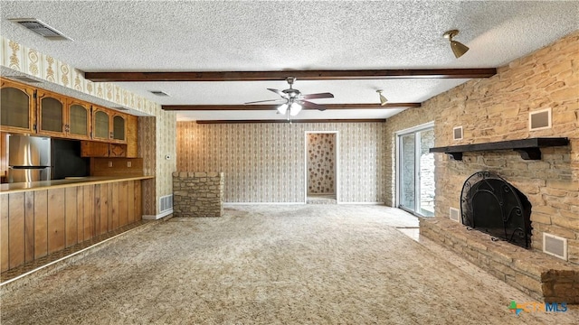162 Lone Oak St, Seguin, TX 78155 - unfurnished living room with carpet floors, a textured ceiling, beam ceiling, ceiling fan, and a fireplace