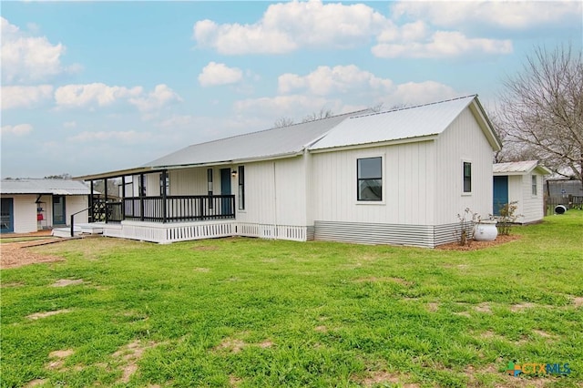 rear view of house featuring metal roof, covered porch, and a lawn