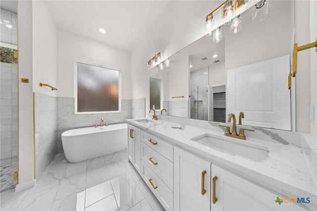 5273 Comanche Dr, Temple, TX 76502 - full bathroom featuring double vanity, a freestanding tub, marble finish floors, a shower stall, and wainscoting