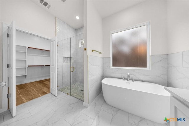 5273 Comanche Dr, Temple, TX 76502 - full bathroom with a freestanding tub, marble finish flooring, a stall shower, a walk in closet, and tile walls