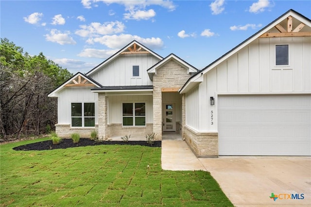 5273 Comanche Dr, Temple, TX 76502 - view of front of home featuring board and batten siding, stone siding, a front lawn, driveway, and an attached garage
