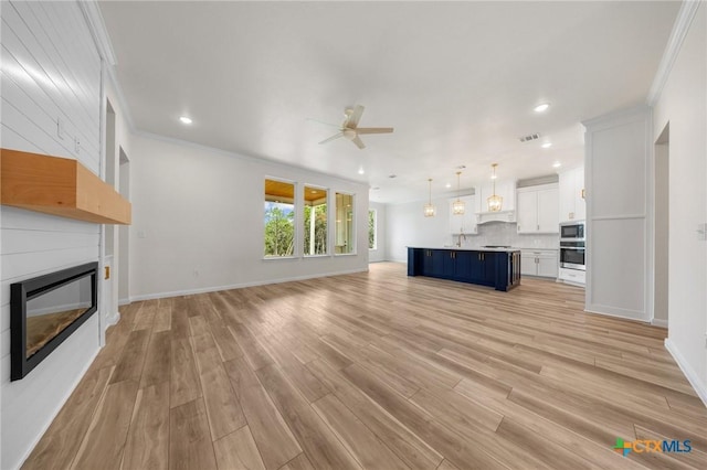 5273 Comanche Dr, Temple, TX 76502 - unfurnished living room with ceiling fan, a glass covered fireplace, ornamental molding, light wood finished floors, and recessed lighting