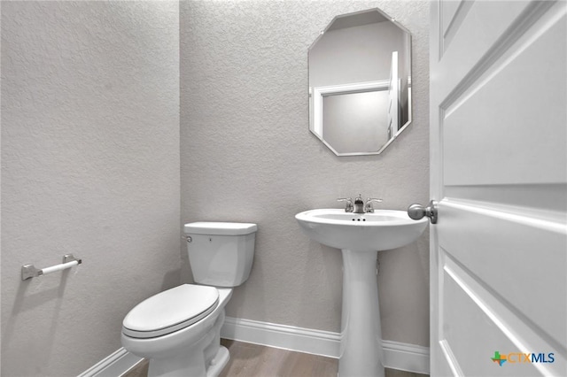 bathroom with toilet and wood-type flooring