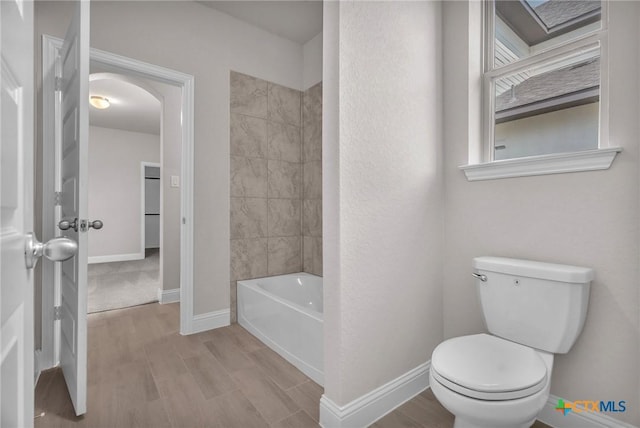 bathroom with hardwood / wood-style flooring, tub / shower combination, and toilet