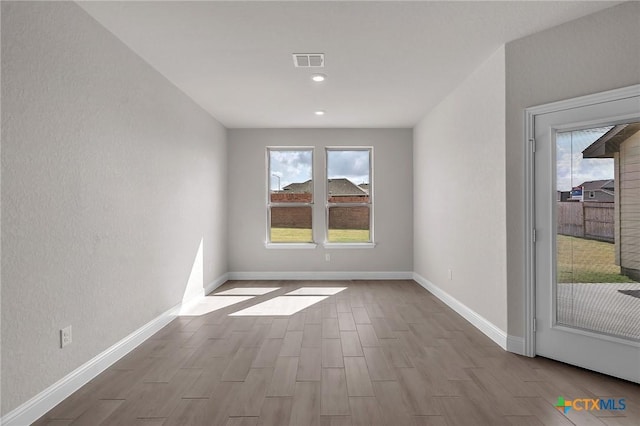 empty room with light hardwood / wood-style floors and a wealth of natural light