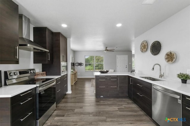 8606 Georgia Ave, Temple, TX 76502 - kitchen with wall chimney range hood, appliances with stainless steel finishes, a sink, light countertops, and dark wood-type flooring