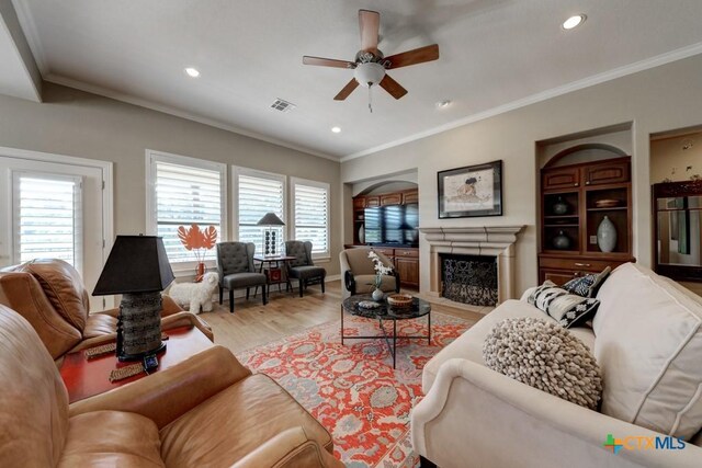 living room featuring ceiling fan, light wood-type flooring, and crown molding