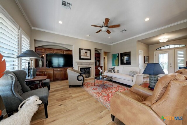 living room featuring ceiling fan, crown molding, and light wood-type flooring