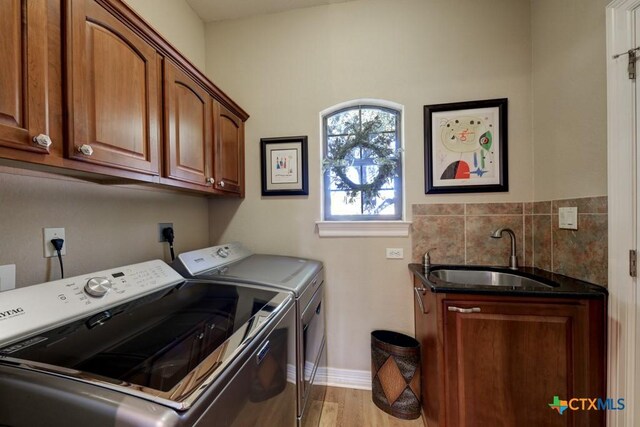 washroom featuring cabinets, light wood-type flooring, sink, and washing machine and clothes dryer