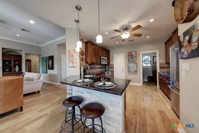 kitchen with stainless steel appliances, tasteful backsplash, light hardwood / wood-style floors, and sink