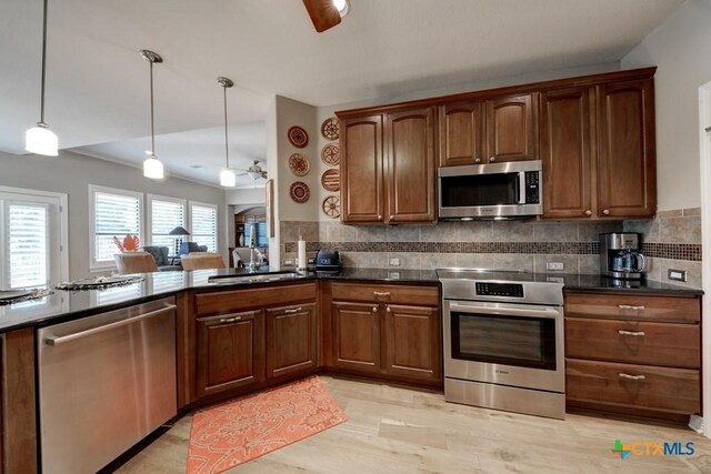 kitchen with decorative backsplash, stainless steel appliances, ceiling fan, and hanging light fixtures