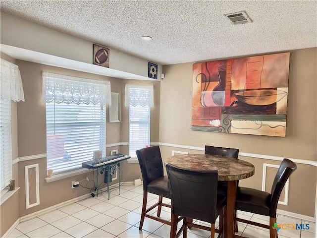 tiled dining space with a textured ceiling