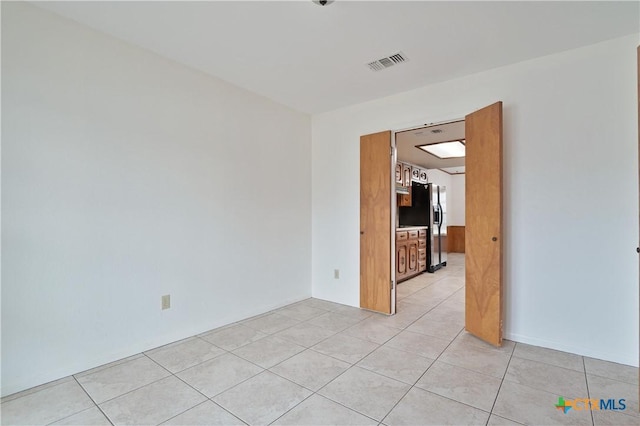 spare room featuring light tile patterned flooring and visible vents