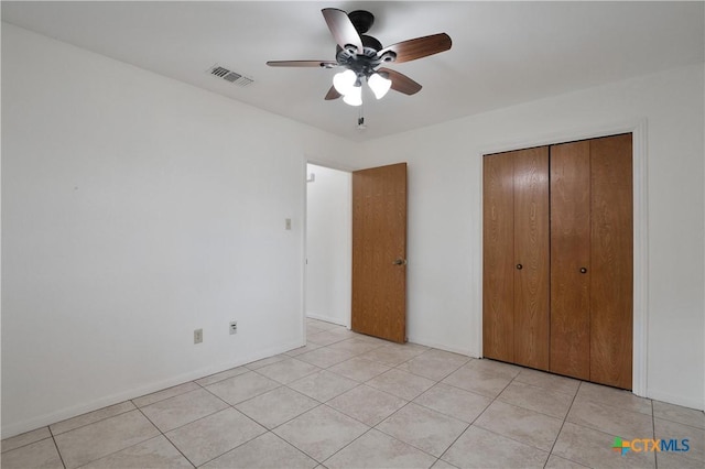 unfurnished bedroom with light tile patterned floors, a ceiling fan, a closet, and visible vents