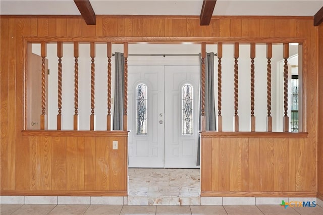 entrance foyer with wood walls, beam ceiling, and tile patterned flooring