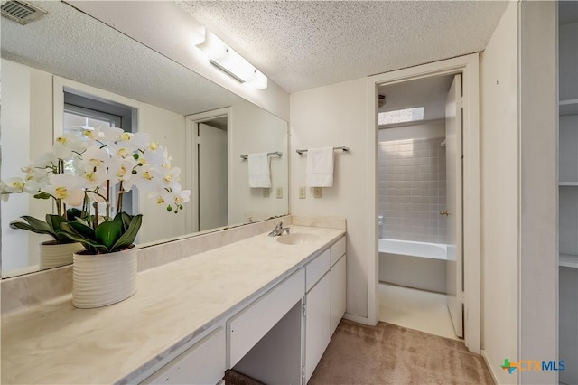 bathroom with vanity, a textured ceiling, and tiled shower / bath