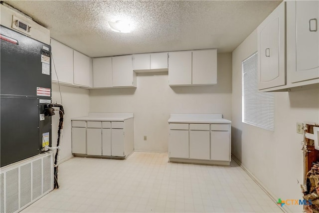 kitchen with white cabinets and a textured ceiling