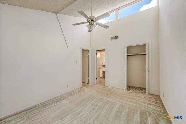 unfurnished bedroom with ceiling fan, light carpet, high vaulted ceiling, and a closet