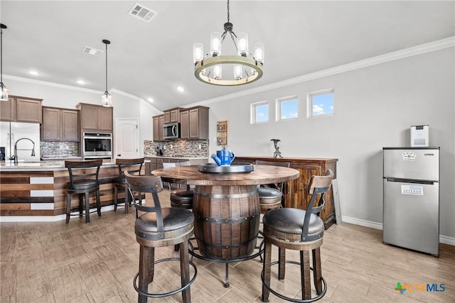 7511 Wind Chime Way, Temple, TX 76502 - dining room with light wood-style floors, crown molding, a chandelier, vaulted ceiling, and recessed lighting