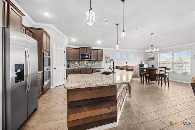 7511 Wind Chime Way, Temple, TX 76502 - kitchen with stainless steel appliances, crown molding, a kitchen island with sink, decorative backsplash, and dark brown cabinets