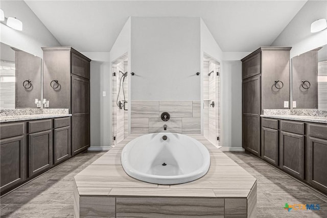7511 Wind Chime Way, Temple, TX 76502 - bathroom featuring two vanities, a bath, tiled shower, and lofted ceiling