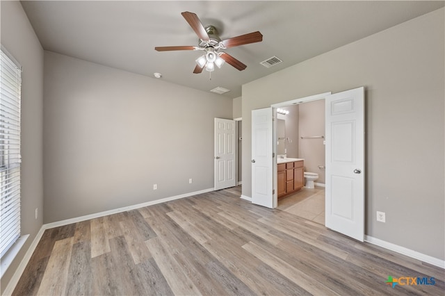 unfurnished bedroom featuring multiple windows, connected bathroom, light hardwood / wood-style flooring, and ceiling fan