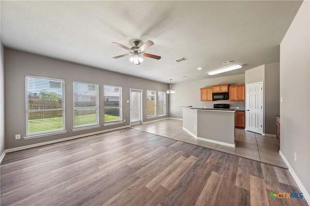 kitchen featuring dark stone counters, tasteful backsplash, light tile patterned floors, and black appliances