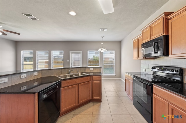 kitchen with decorative backsplash, sink, black appliances, light tile patterned floors, and a center island with sink