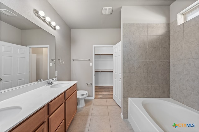 bathroom with tile patterned flooring, vanity, toilet, and a tub