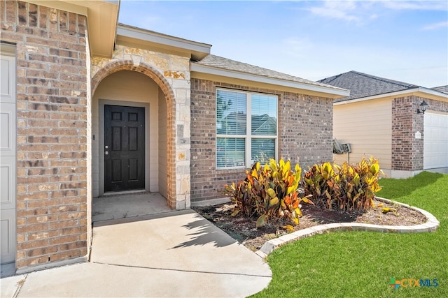 doorway to property with a yard and a garage