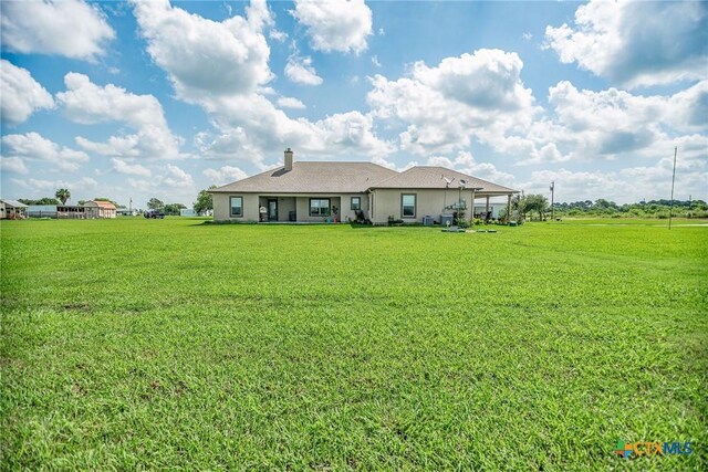 196 Garza Rd, Port Lavaca, TX 77979 - back of property featuring a lawn, stucco siding, and a chimney