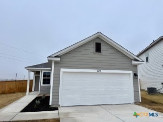 view of front of house with an attached garage, central AC, driveway, and fence