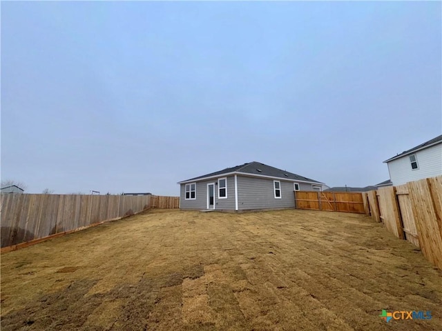 rear view of house with a lawn and a fenced backyard