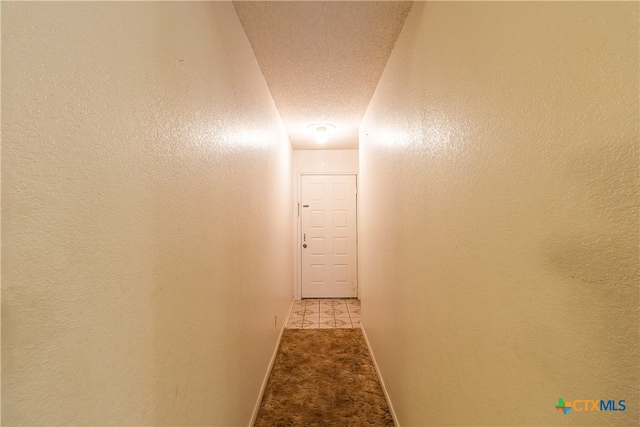 hallway featuring light carpet and a textured ceiling