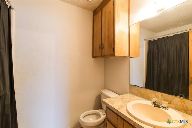 bathroom with curtained shower, vanity, a textured ceiling, and toilet