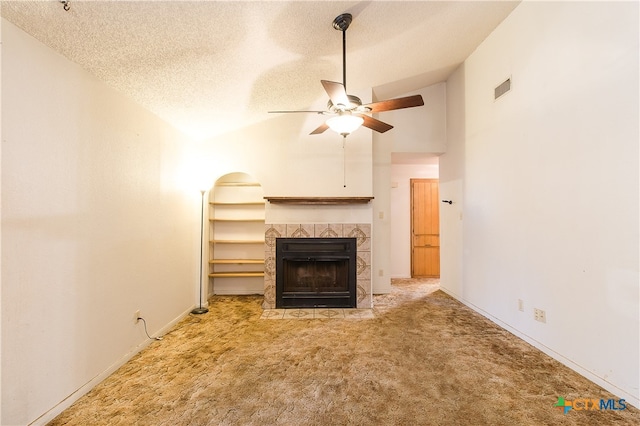 unfurnished living room featuring a textured ceiling, light carpet, high vaulted ceiling, a tile fireplace, and ceiling fan