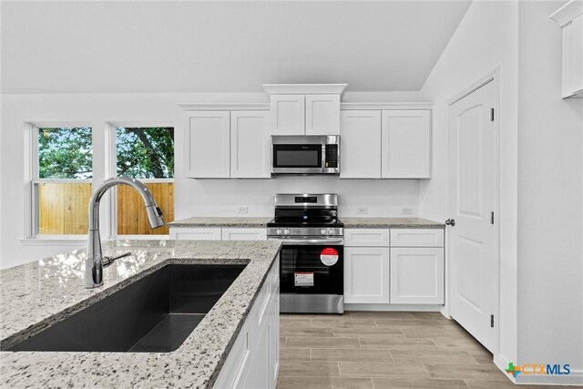 9820 Tarabon Dr, Killeen, TX 76542 - kitchen with appliances with stainless steel finishes, white cabinets, light stone counters, and light wood-type flooring