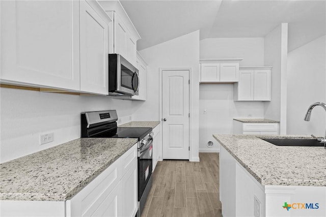 9820 Tarabon Dr, Killeen, TX 76542 - kitchen with stainless steel appliances, white cabinets, lofted ceiling, wood finish floors, and light stone countertops