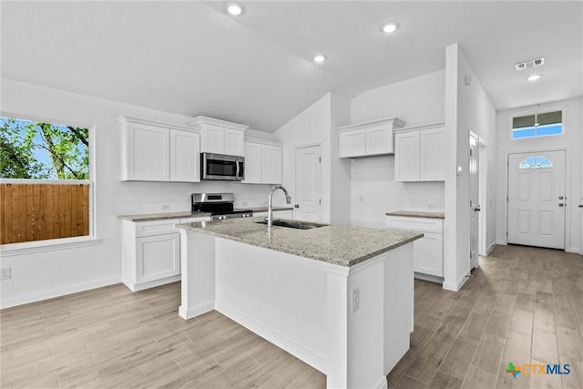 9820 Tarabon Dr, Killeen, TX 76542 - kitchen featuring stainless steel appliances, an island with sink, light stone countertops, light wood finished floors, and lofted ceiling