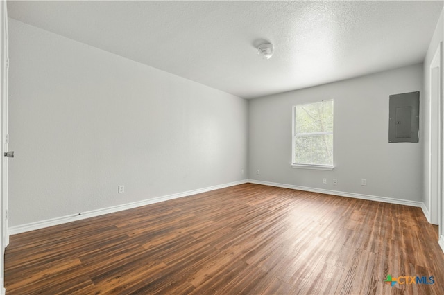 unfurnished room with electric panel and dark hardwood / wood-style flooring