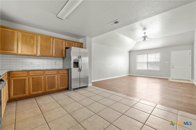 kitchen with ceiling fan, backsplash, vaulted ceiling, stainless steel refrigerator with ice dispenser, and light tile patterned floors