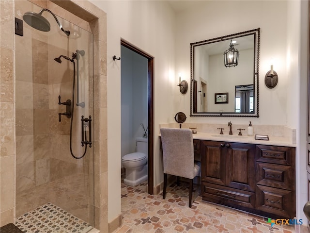 bathroom featuring toilet, vanity, and tiled shower